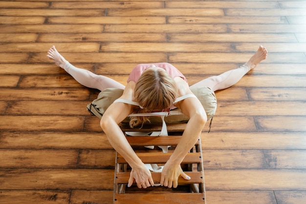 Rijpe vrouw doet rekoefeningen op Yoga Backbend Bench in studio