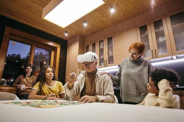 Foto rijpe vrouw en haar twee interraciale kleinkinderen kijken naar senior man in vr-headset