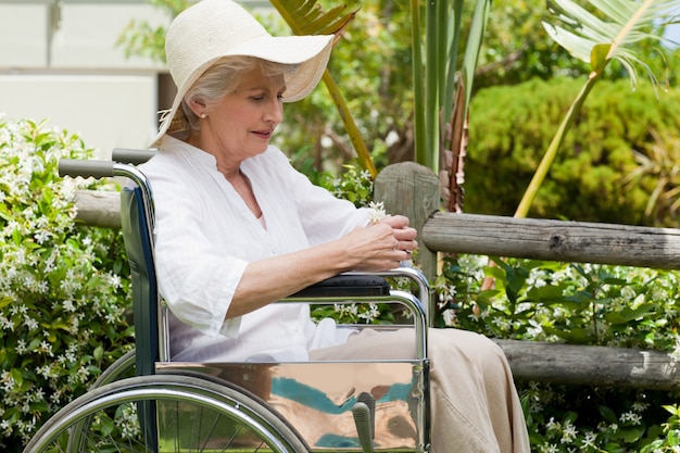 Rijpe vrouw in haar rolstoel in de tuin