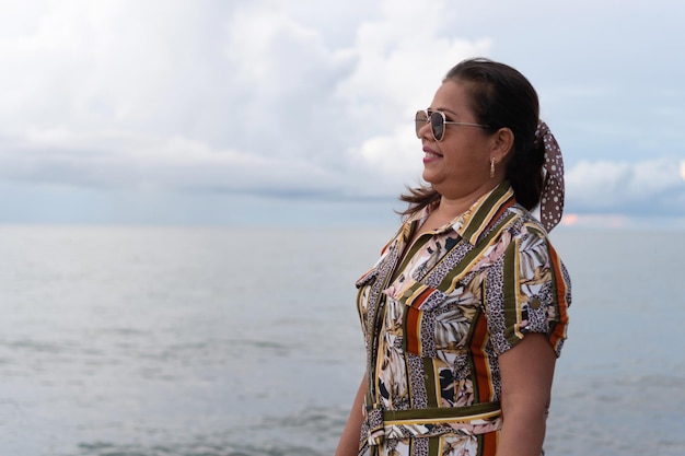 Rijpe vrouw in park met strand op de achtergrond