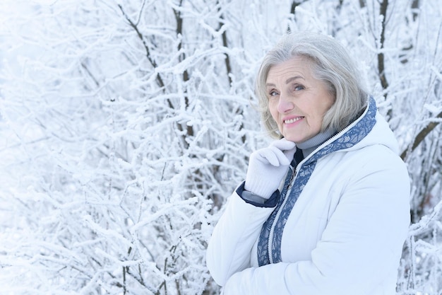 Rijpe vrouw in winterkleren poseren buitenshuis in een goed humeur