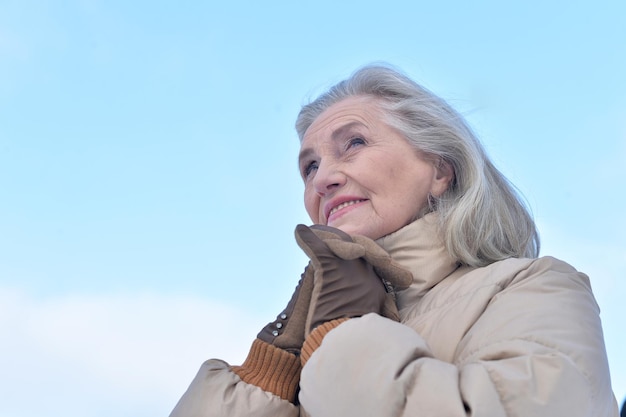 Rijpe vrouw in winterkleren poseren buitenshuis in een goed humeur