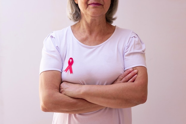 Rijpe vrouw met een roze lint dat op wit wordt geïsoleerd. Afbeelding van de maand van de bewustmaking van borstkanker.