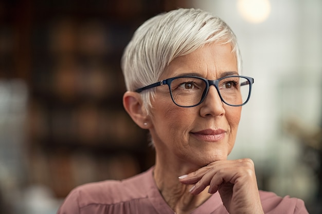 Rijpe vrouw met oogglazen het denken