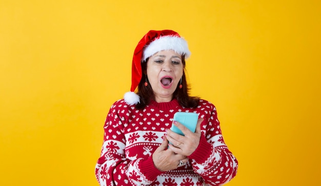 Rijpe vrouw met smartphone kerst gele achtergrond