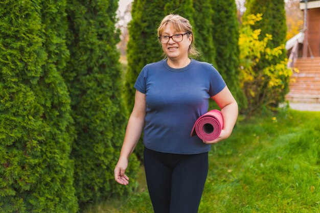 Rijpe vrouw op yoga-retraite in de buitenlucht die langs het pad door de camping loopt