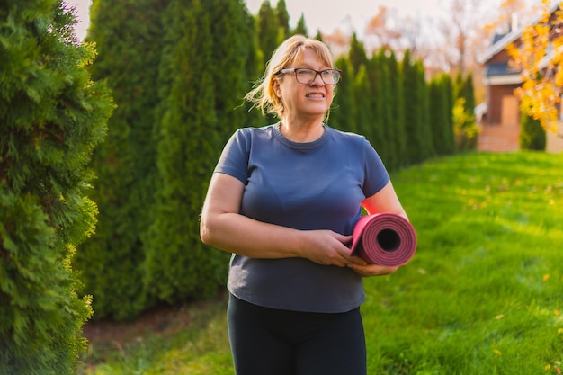 Rijpe vrouw op yoga-retraite in de buitenlucht die langs het pad door de camping loopt