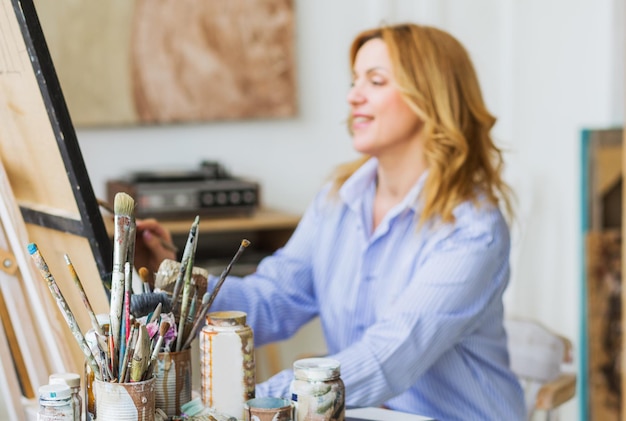 Rijpe vrouw schilderij penseel op canvas in studio.