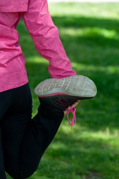 Rijpe vrouw traint in een park en doet rekoefeningen met een chirurgisch masker tijdens de covid-19-pandemie