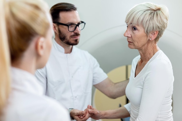 Foto rijpe vrouwelijke patiënt die twijfels heeft over de mri-scanprocedure en met artsen praat vóór het onderzoek in het ziekenhuis