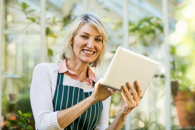 Rijpe vrouwelijke tuinman die tabletcomputer met behulp van