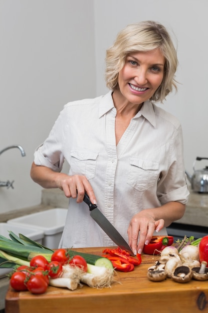 Rijpe vrouwen hakkende groenten in keuken