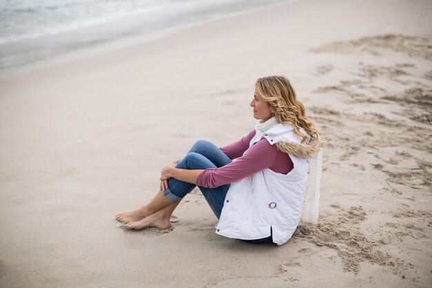 Rijpe vrouwenzitting op een strand