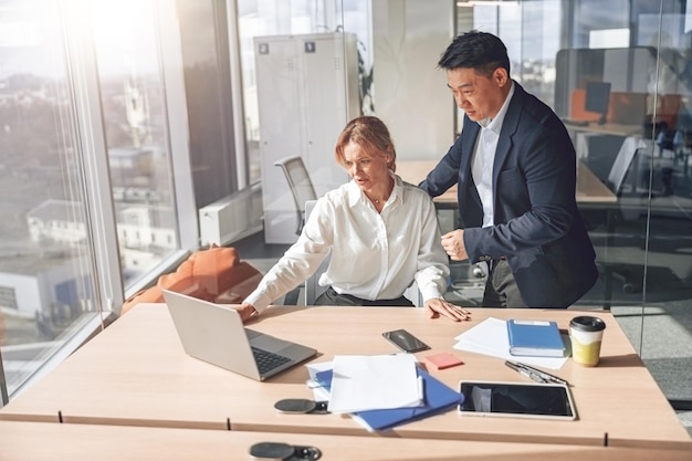 Rijpe zakenvrouw toont aan collega haar project in laptop Zakelijke relatie concept