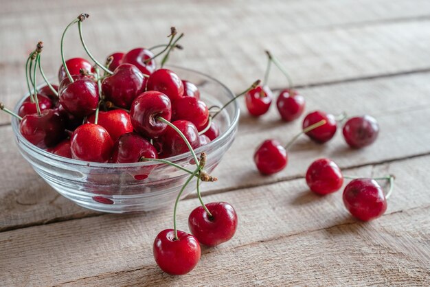 Rijpe zoete kersen in een glazen kom op houten tafel met groene bokeh achtergrond zomerfruit