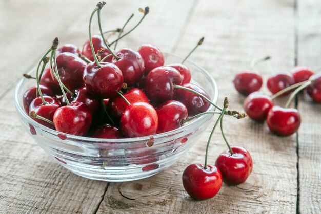 Rijpe zoete kersen in een glazen kom op houten tafel met groene bokeh achtergrond, zomerfruit