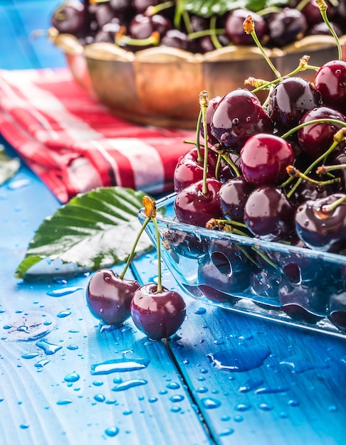 Rijpe zoete kersen op blauwe woden tafel met waterdruppels.