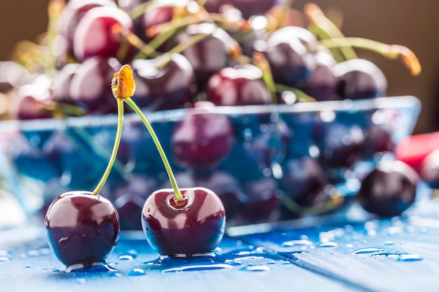 Rijpe zoete kersen op blauwe woden tafel met waterdruppels.