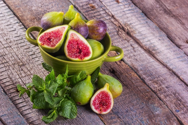 Rijpe zoete vijgen in een groene kom op een houten tafel