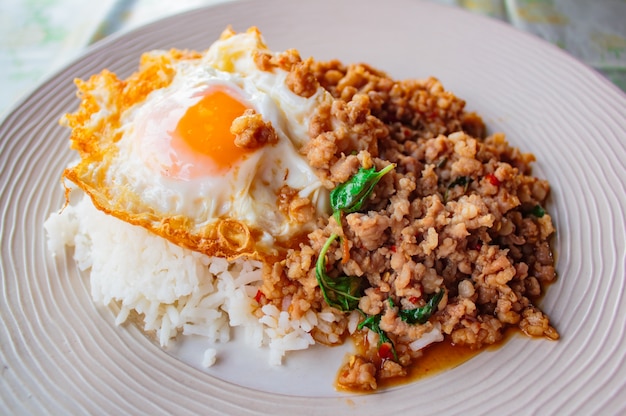 Rijst bedekt met geroerbakte varkensvlees en basilicum geserveerd met gebakken ei.