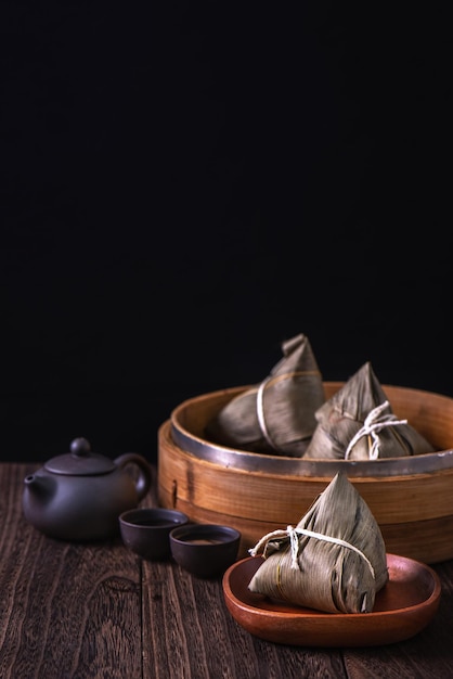 Rijst knoedel zongzi Stelletje Chinese traditionele gekookt voedsel op houten tafel over zwarte achtergrond concept van Dragon Boat Festival close-up kopie ruimte