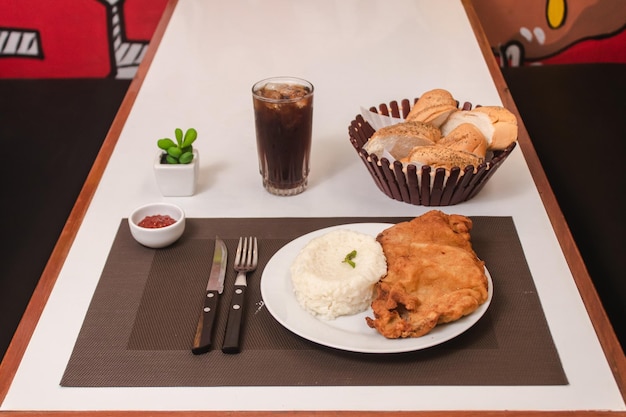 Rijst met milanesa geserveerd op een bord met frisdrank en brood