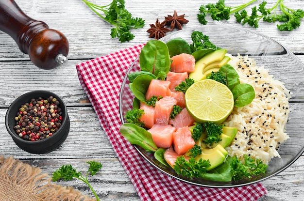 Rijst met zalm, avocado en spinazie In een zwarte plaat op een houten achtergrond Bovenaanzicht Vrije ruimte voor uw tekst Plat leggen