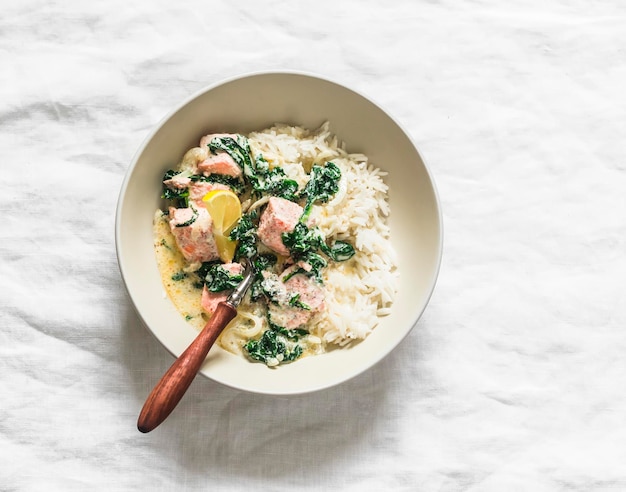 Foto rijst met zalm, spinach, roomsaus, stoofpot, heerlijke lunch op een lichte achtergrond.