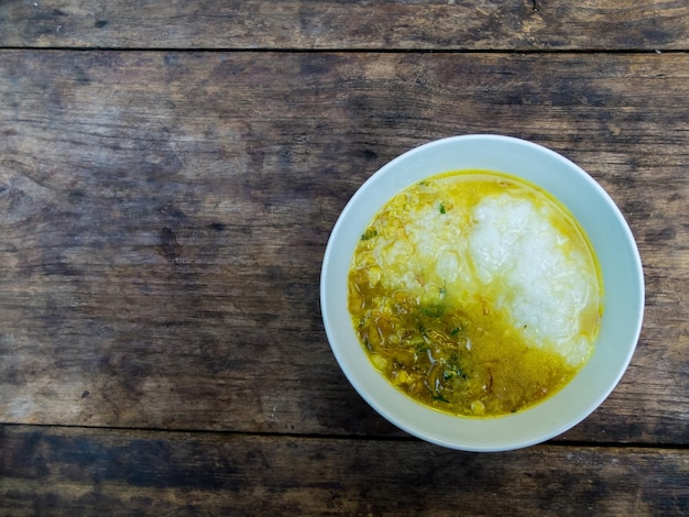 Rijst pap met varkensvlees en curry in thaise stijl op zwarte houten tafel