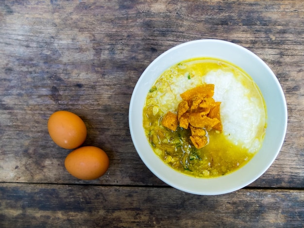 Foto rijst pap met varkensvlees en curry in thaise stijl op zwarte houten tafel