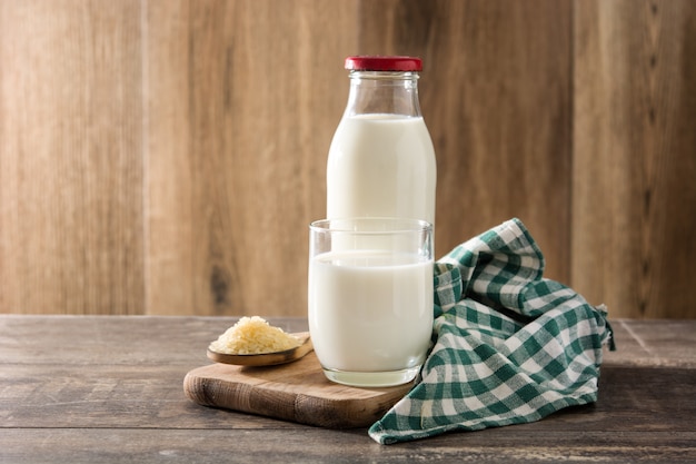 Rijstmelk in glas en fles op houten tafel