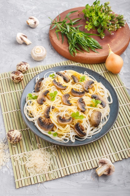 Rijstnoedels met champignons champignons, eiersaus en oregano op een grijze betonnen achtergrond. zijaanzicht.