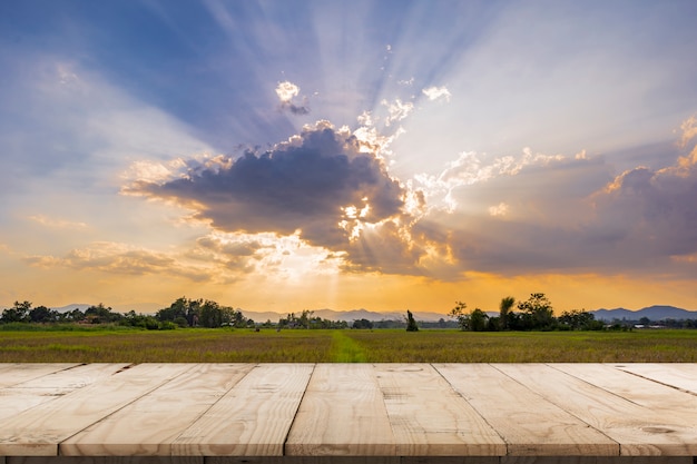 Rijstveld zonsondergang en lege houten tafel voor productweergave en montage.