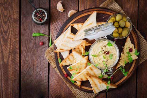 rillette, toast, olijven en kruiden op een houten bord. .