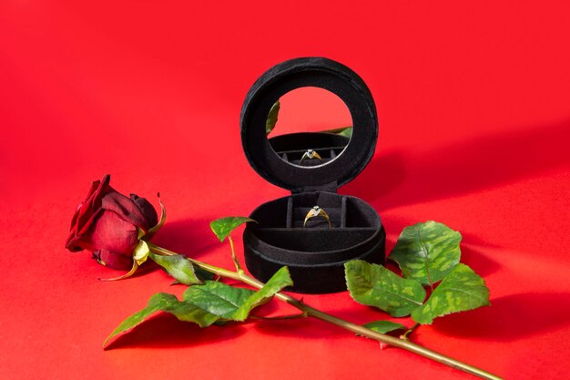 A ring in a casket a red rose and red background motifs for the theme of marriage proposal or gifts for valentines day