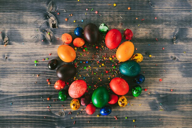 Кольцо пасхальных яиц на деревянном фоне круг разноцветных яиц и декоративной сахарной пудры