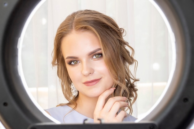 Ring lamp. photographing a model in a beauty salon after applying makeup and hairstyles. in the eyes of a beautiful girl model reflected a ring lamp.