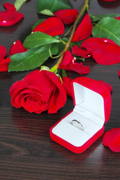 Ring omringd door rozen en bloemblaadjes op houten tafel close-up