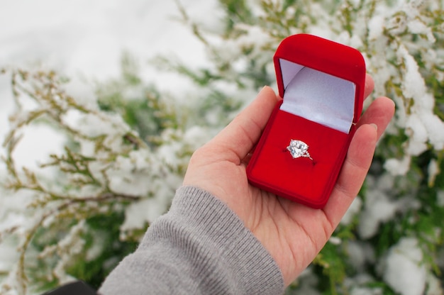 A ring with a large gemstone in a red box in the hand on a blurry background