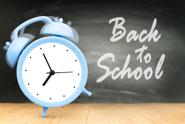 Ringing alarm clock on blackboard background, concept back to school