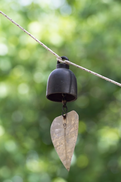 녹색과 bokeh 배경으로 밧줄에 울리는 벨