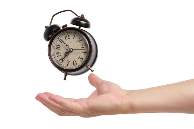 Ringing and hovering old retro alarm clock above hand on white background