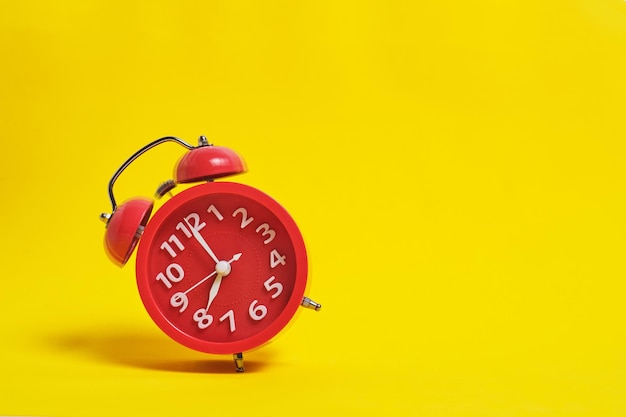 Ringing red alarm clock on yellow background.