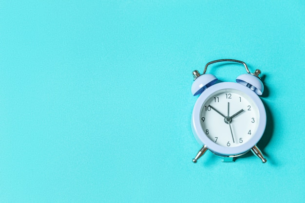 Ringing twin bell alarm clock Isolated on blue pastel background