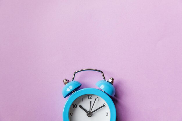 Ringing twin bell vintage classic alarm clock Isolated on purple violet pastel colourful background. Rest hours time of life good morning night wake up awake concept. Flat lay top view copy space