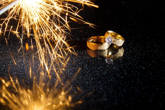 Кольца на темном фоне. Свадебные кольца. Ювелирные изделия. Бенгальские огни