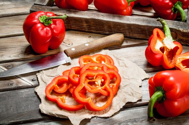 Rings of sweet pepper on paper with a knife and a whole pepper on tray