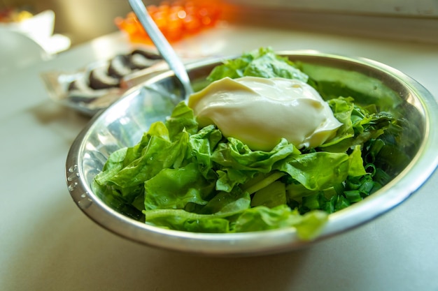 Photo rinsed green lettuce with sour cream in a bowl