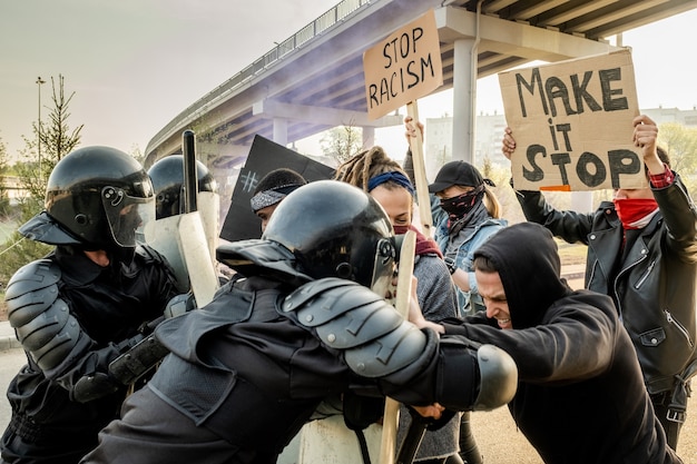 写真 集会で彼らと戦っている間、盾で抗議者を押すヘルメットの機動隊