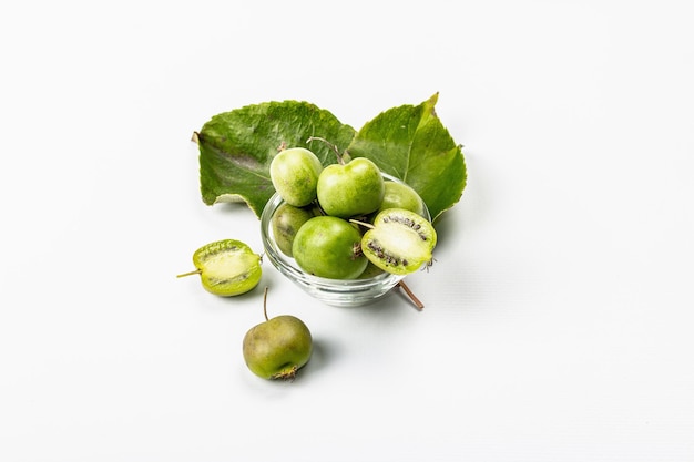 Ripe Actinidia arguta or kiwi isolated on white background. Branches of fresh fruits with green leaves, mockup, template